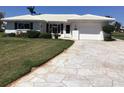 Charming single-story home featuring a well-manicured lawn and a patterned concrete driveway at 1002 Pussywillow Ln, Bradenton, FL 34208