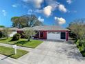 Charming home with well-manicured lawn, mature landscaping, and attached two-car garage at 1102 Springtime Dr, Holiday, FL 34691
