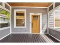 Beautiful covered front porch with a wooden door, complemented by natural light and wood flooring at 114 E Emily St, Tampa, FL 33603