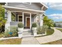 Inviting front porch featuring a classic wood door, decorative plants, and a secure SimpliSafe system at 114 E Emily St, Tampa, FL 33603