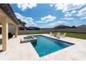 Resort style pool and spa, beautiful travertine decking and outdoor seating in a lovely backyard at 11966 Climbing Fern Ave, Riverview, FL 33579