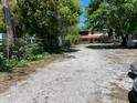 View of a large gravel parking area and the home's red accented screened porch at 14633 Sassandra Dr, Odessa, FL 33556