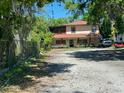 Two-story home boasts a large parking area and a cozy screened porch, framed by mature trees at 14633 Sassandra Dr, Odessa, FL 33556