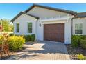 Home featuring a brown garage door with a brick driveway and well-maintained landscaping at 16710 Shell Bay Dr, Land O Lakes, FL 34638