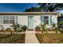 Charming single-story home featuring a light-blue door, light-blue shutters, and lush landscaping at 2261 Queen S St, St Petersburg, FL 33712