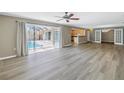 Open living room with wood flooring, ceiling fan, and sliding glass doors to the screened-in pool at 2312 Heron Cir, Clearwater, FL 33762