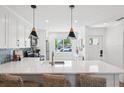 Bright kitchen with quartz countertops, blue backsplash, stainless steel appliances, and modern lighting at 438 62Nd St, Holmes Beach, FL 34217