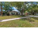 Charming single-story home featuring a large tree, two-car garage, and well-maintained lawn at 9044 Lynwood Dr, Seminole, FL 33772
