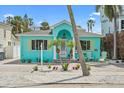 Charming turquoise coastal home with a well-manicured lawn and a cozy front porch seating area at 106 23Rd Ave, St Pete Beach, FL 33706