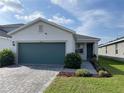 Attractive one-story home with a pristine lawn, brick paver driveway, and teal garage at 11833 Clare Hill Ave, Riverview, FL 33579