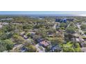 Expansive aerial view of a neighborhood with tree coverage and water in the distance, offering a sense of community at 1201 Kapok Kove Cir, Clearwater, FL 33759