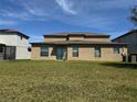 Home's backyard featuring a well-maintained lawn with sliding glass door and windows to the house at 14050 Arbor Pines Dr, Riverview, FL 33579