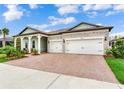Charming exterior featuring a two-car garage, covered front porch with seating, and well-manicured landscaping at 18636 Sailors Delight Pass, Land O Lakes, FL 34638