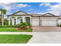 Beautiful front exterior of a home with a brick driveway, two-car garage, and a charming covered front porch at 18636 Sailors Delight Pass, Land O Lakes, FL 34638