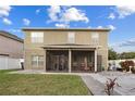 View of the home's back exterior and a screened patio, perfect for outdoor relaxation and entertainment at 19214 Early Violet Ne Dr, Tampa, FL 33647