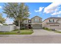 The front of the house has mature trees, a two-car garage, and an arched entrance, creating a welcoming facade at 19214 Early Violet Ne Dr, Tampa, FL 33647