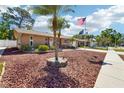 Inviting single-story home boasts a landscaped front yard, palm tree, and patriotic flag waving proudly at 2033 Whitney Dr, Clearwater, FL 33760