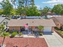 Charming single-story home featuring a well-maintained lawn, attached garage, and patriotic flag display at 2033 Whitney Dr, Clearwater, FL 33760
