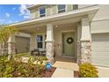 Inviting front porch with stone accents, a seating area, and a charming green front door at 33645 Elm Hill Br, Wesley Chapel, FL 33545