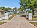 A long brick driveway leads to a blue home with a well-maintained front yard and mature trees at 4419 Swift Cir, Valrico, FL 33596