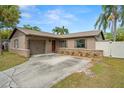 Single-story home with stone accents, driveway, lawn, landscaping, garage and covered entryway at 611 Limetree Dr, Oldsmar, FL 34677