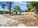 A quaint one-story home with a car port, fresh light green paint and tidy yard surrounded by trees at 9208 N 27Th St, Tampa, FL 33612