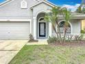 Inviting front entrance with a black framed door, landscaping, and an attached two car garage at 11414 Weston Course Loop, Riverview, FL 33579