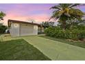 Home featuring an attached garage and a long driveway surrounded by green lawn at 11705 Ibis Ln, Port Richey, FL 34668