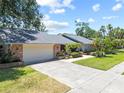 Charming single-story home with a well-manicured lawn, palm trees and a two-car garage at 1810 Pine Hill Dr, Safety Harbor, FL 34695
