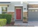 Inviting front entrance features a red door, stone accents, manicured bushes, and paver walkway at 19309 Prairie Tree Pl, Tampa, FL 33647