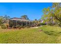 Spacious backyard with a screened pool area, lush green grass and mature trees for privacy at 3109 Tarpon Woods Blvd, Palm Harbor, FL 34685