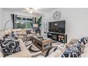 Bright and airy living room featuring comfortable seating, large TV, and a sliding door to the patio at 6748 Ripple Pond Loop, Zephyrhills, FL 33541