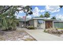 Charming single-story home with mature trees and a cozy front yard seating area at 101 Gulf Blvd, Belleair Beach, FL 33786