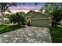 Charming home showcasing an attached garage, well-kept lawn, and a vibrant orange front door at sunset at 1187 Mistwood Dr, Tarpon Springs, FL 34688