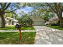 Charming home showcasing an attached garage, well-kept lawn, and a vibrant orange front door at 1187 Mistwood Dr, Tarpon Springs, FL 34688