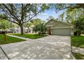 Charming home showcasing an attached garage, well-kept lawn, and a vibrant orange front door at 1187 Mistwood Dr, Tarpon Springs, FL 34688