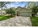 Inviting single-story home features a well-maintained lawn, lush landscaping, and a two-car garage at 1187 Mistwood Dr, Tarpon Springs, FL 34688