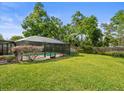 View of the backyard featuring a screened enclosure around the pool and a well-maintained lawn at 16320 Bonneville Dr, Tampa, FL 33624