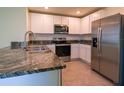 Modern kitchen features stainless steel appliances, granite countertops, and white cabinetry at 16805 Delia St, Wimauma, FL 33598
