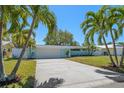 Inviting home featuring a well-maintained lawn, a spacious driveway, and mature palm trees at 4036 Church Creek Pt, Largo, FL 33774