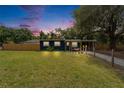 Home with a manicured lawn, covered carport, and inviting porch swing beneath a colorful sky at dusk at 901 King St, Plant City, FL 33563
