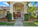 Inviting front entrance featuring a striking red door, manicured landscaping, and an arched entryway at 17108 Longacres Ln, Odessa, FL 33556