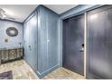 Hallway with an antique dresser, grey wood-look floors and blue colored walls at 19816 Gulf Boulevard # 201, Indian Shores, FL 33785