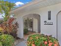 Covered front entryway with tropical landscaping, stone tile and decorative house number at 3323 Ringwood Mdw, Sarasota, FL 34235