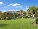 Spacious front yard with verdant lawn, mature palms, and colorful landscaping offering great curb appeal at 3323 Ringwood Mdw, Sarasota, FL 34235