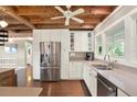 Bright kitchen with wooden ceiling, stainless steel appliances, and white cabinetry with stone countertops at 7500 141St St, Seminole, FL 33776