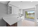 Well-lit kitchen boasts white cabinets, quartz countertops, and a sliding glass door to backyard at 10108 36Th E Ct, Parrish, FL 34219