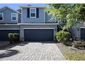 Beautiful townhouse showcasing a gray stone driveway and a two-car garage with manicured landscaping at 1110 Rose Blossom Ct, Tampa, FL 33613