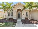 Charming home featuring an arched entryway, lush landscaping, and a well-maintained lawn at 12519 Safari Ln, Riverview, FL 33579