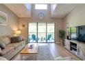 Bright living room featuring vaulted ceilings and a sliding glass door to a balcony with blue Adirondack chairs at 1309 Pine Ridge E Cir # H3, Tarpon Springs, FL 34688